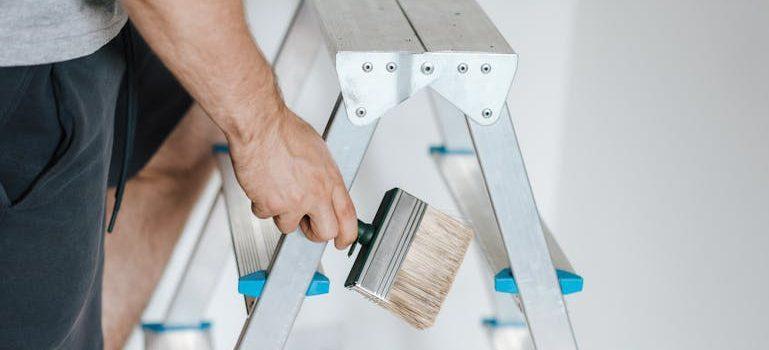 A man climbing a ladder to paint the wall.