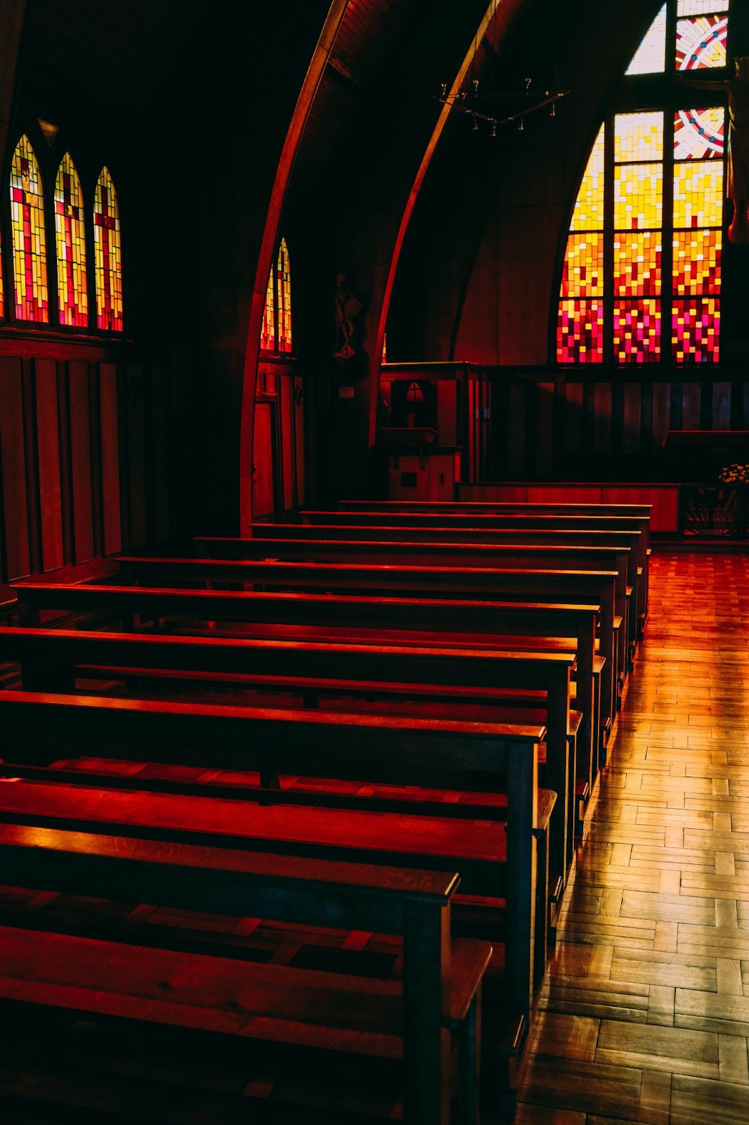 A church with pews, an altar, and stained-glass windows.