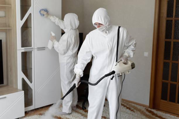 A group of people in white protective suits cleaning a room

Description automatically generated