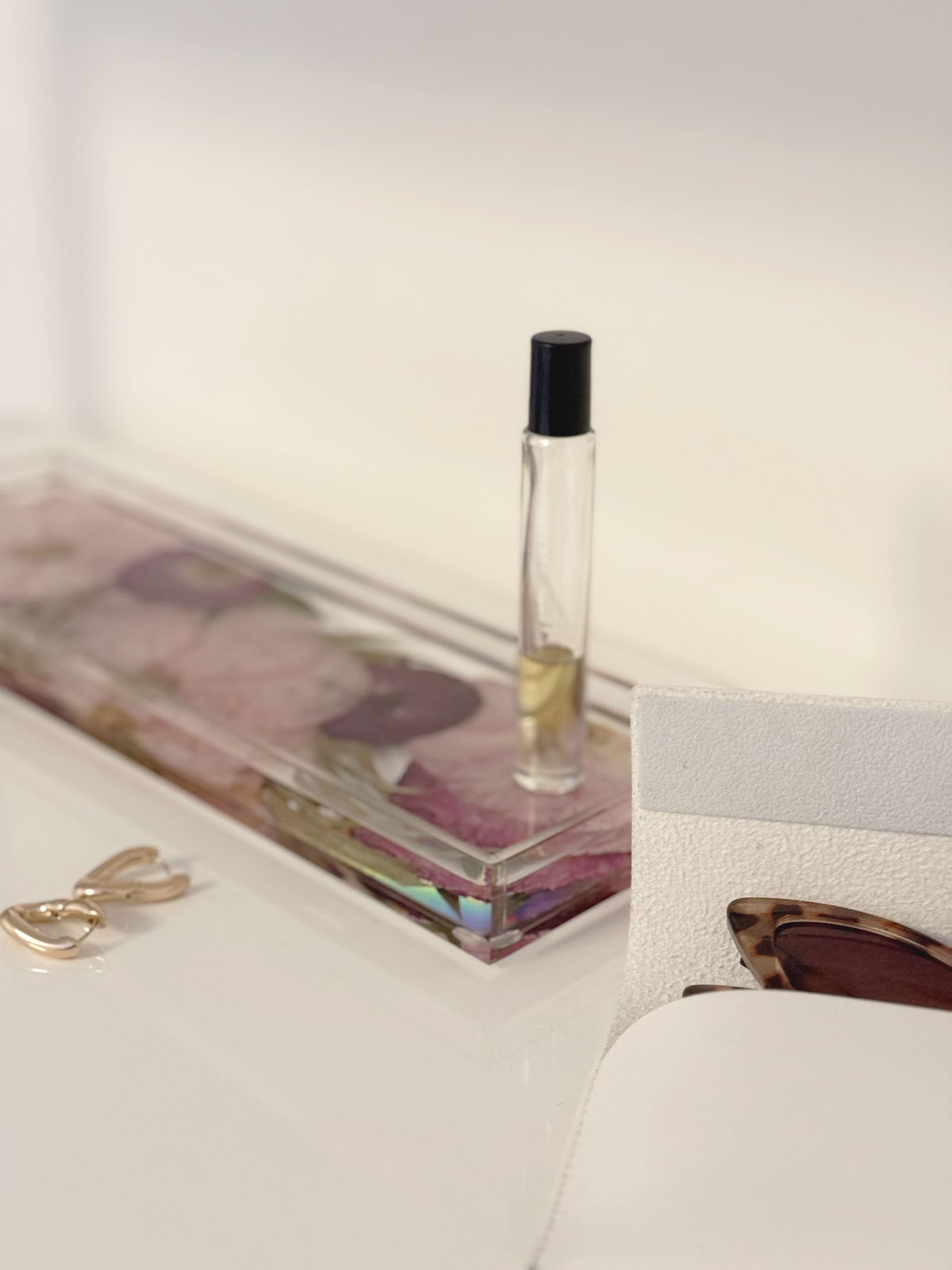 a resin display tray with pressed flowers with jewelry and other accessories on top