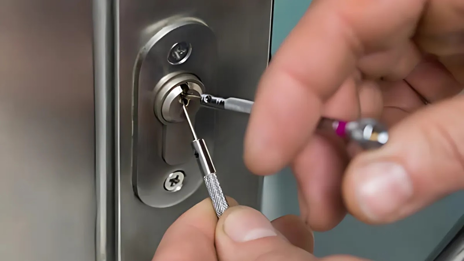 A locksmith uses tools to remove a broken key from a door lock.