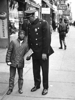 Lloyd Sealy is standing next to a young boy on the sidewalk. Sealy is looking down towards the child.