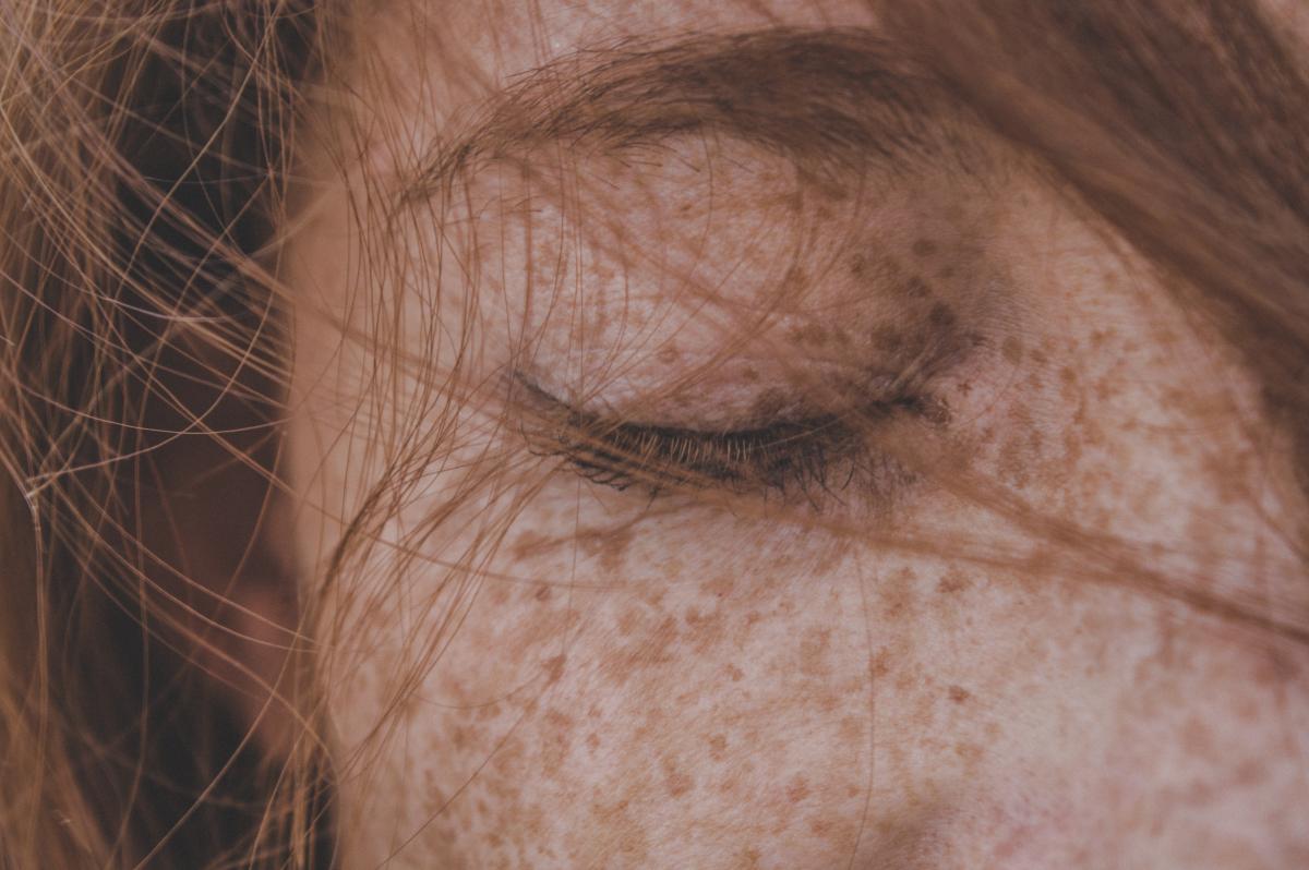 A close-up photograph of a person's closed eye