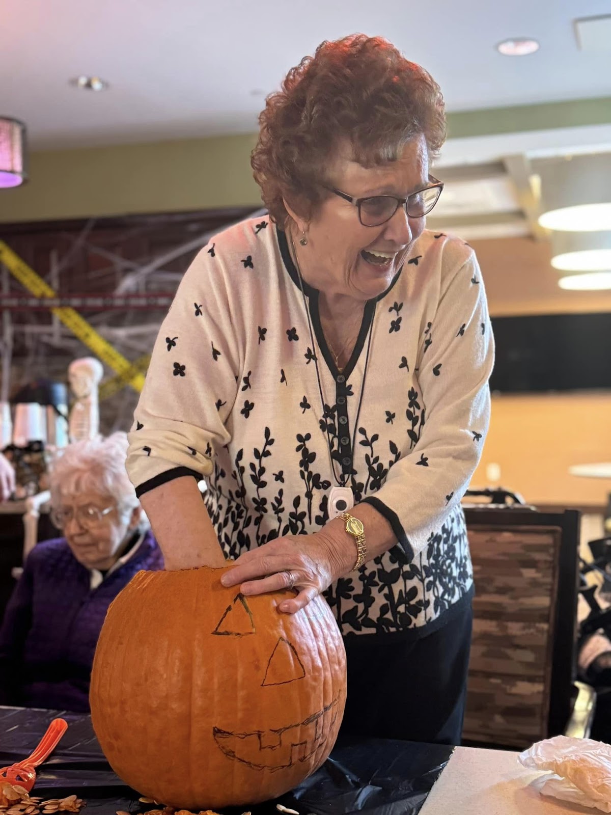 An assisted living resident pumpkin carving with her hand inside the pumpkin