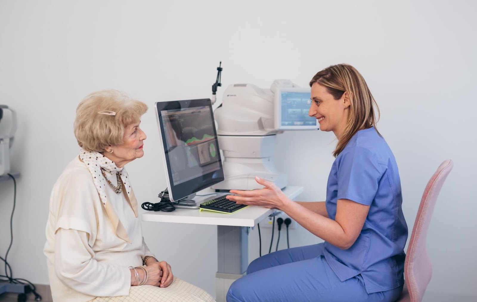 A smiling optometrist explains macular degeneration and treatment options with their attentive senior patient.