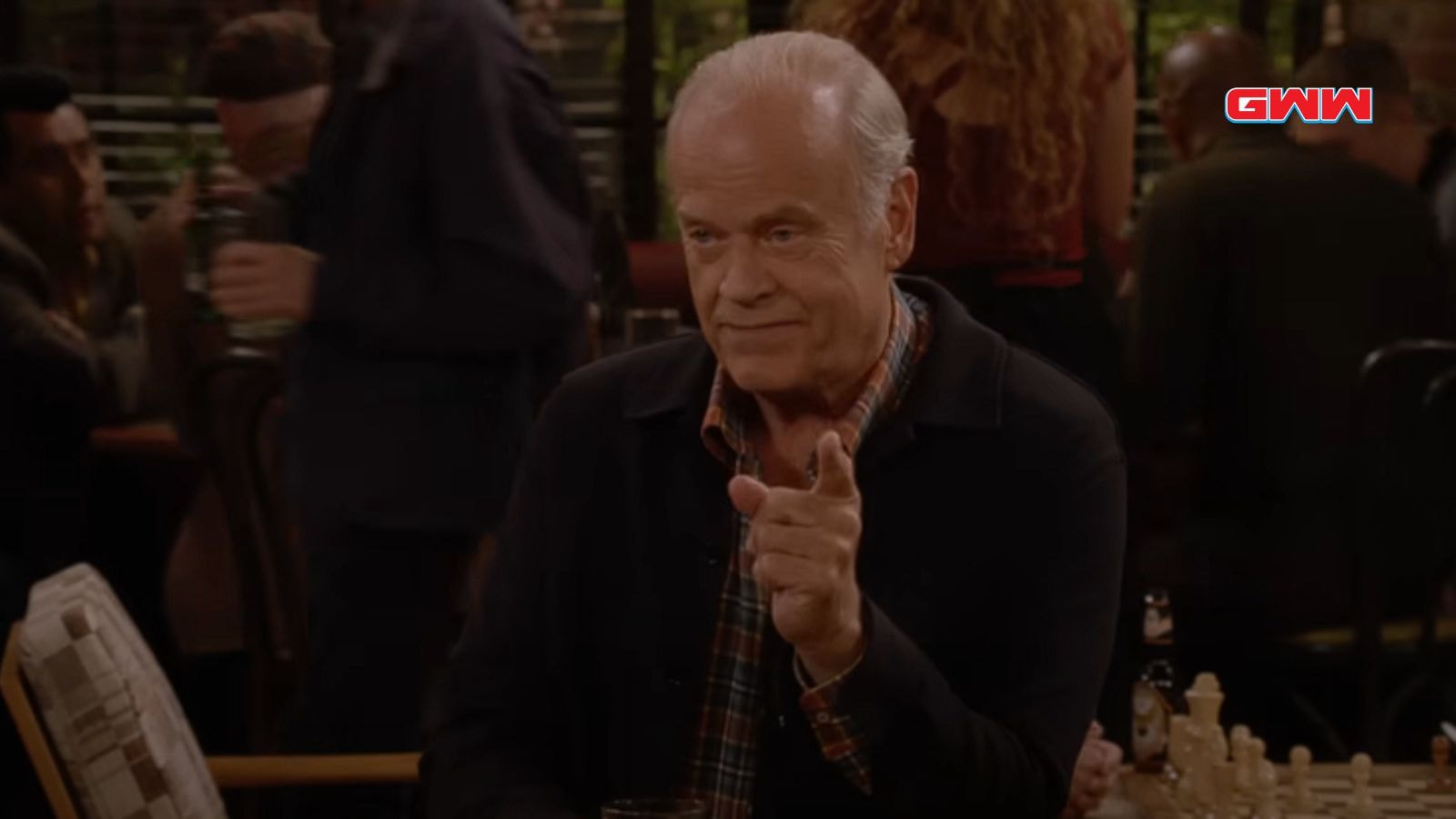 Kelsey Grammer gesturing while having a conversation in a crowded room.