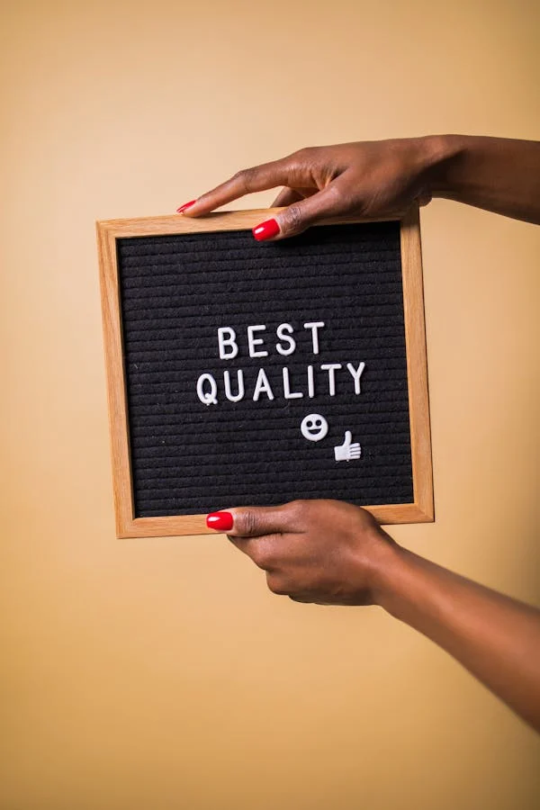 hand holding photoframe with 'BEST QUALITY' written on it with black canvas bg, a smile and thumbs up logo below text