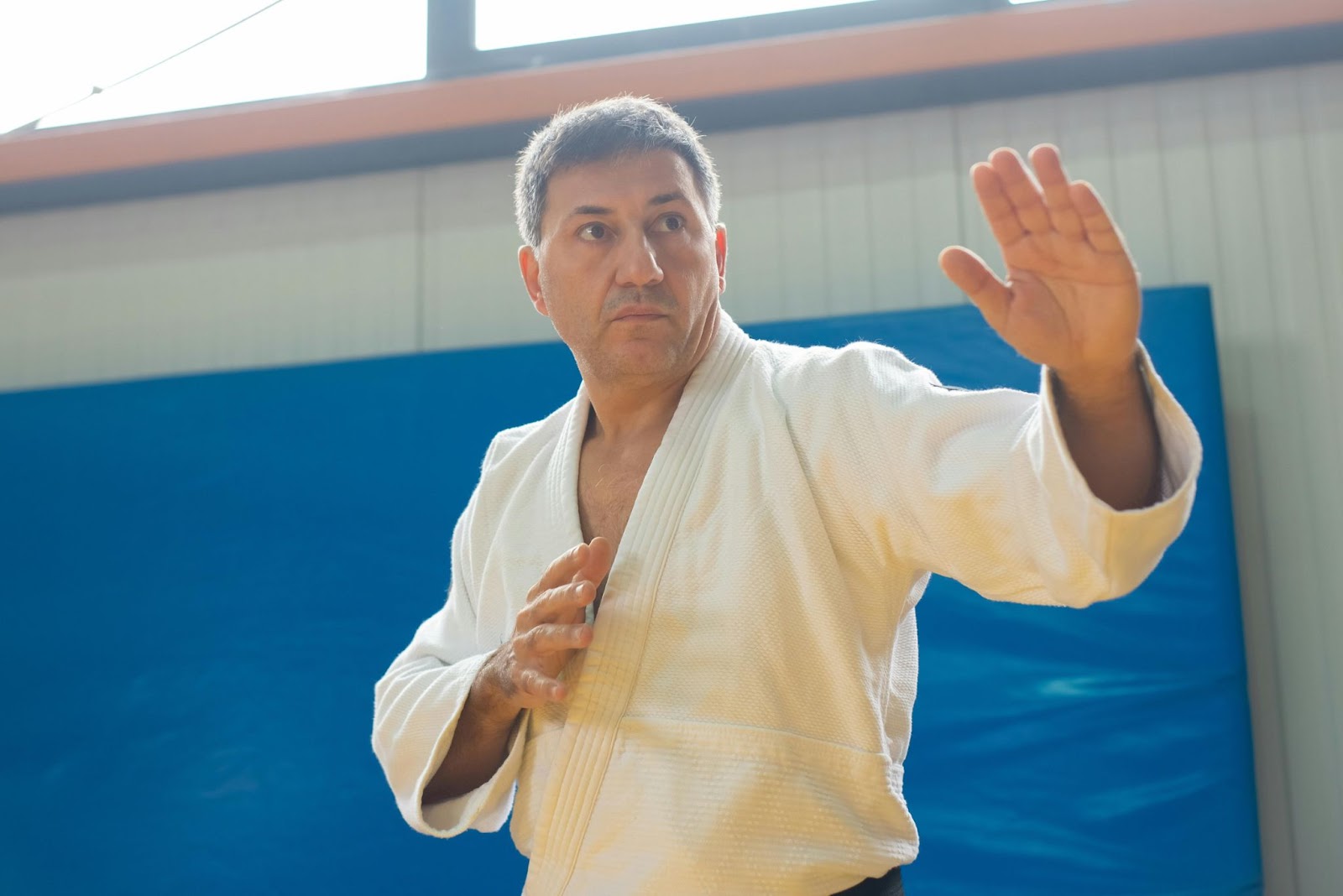 A martial arts instructor in a traditional uniform demonstrates a balanced stance with focused posture.