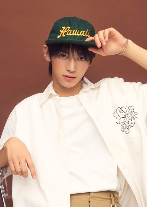 This contains an image of Hanjin's wearing a white shirt and green hat is holding his cap over his head