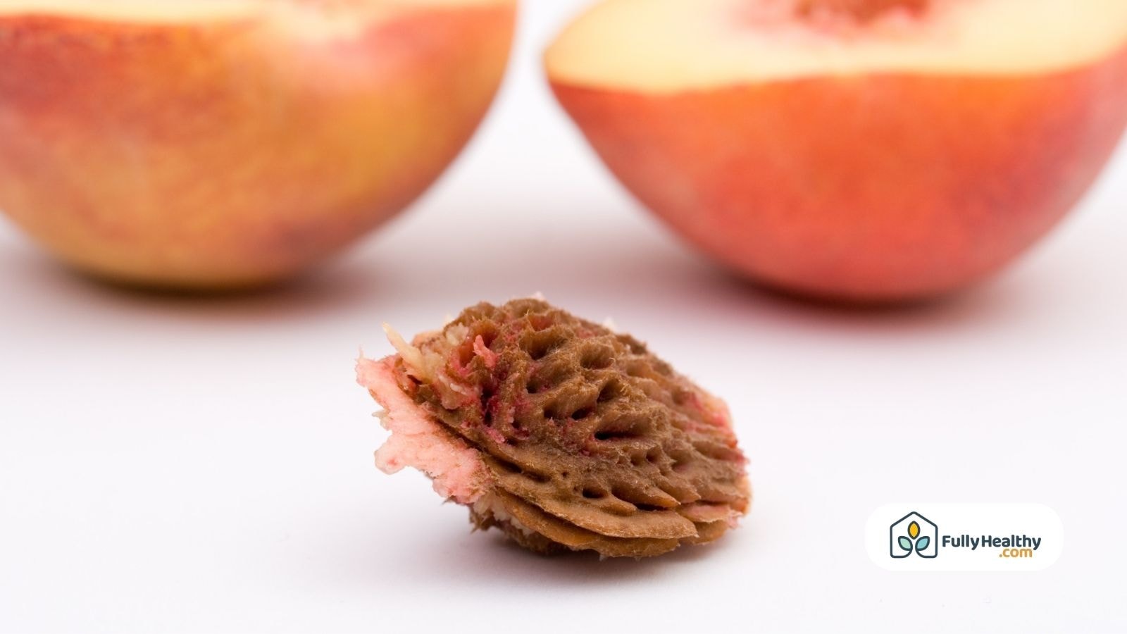 Peach pit and halved peach on white background close-up