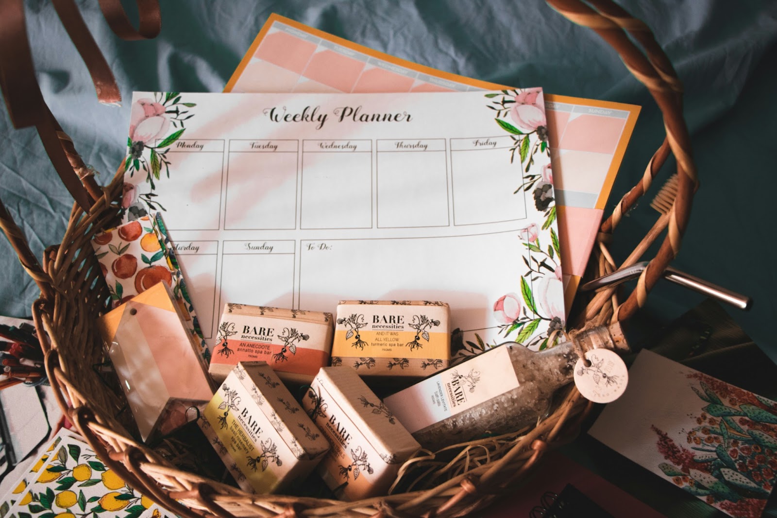 a wooden basket which is filled with two papered planners and multiple variations of hand soaps