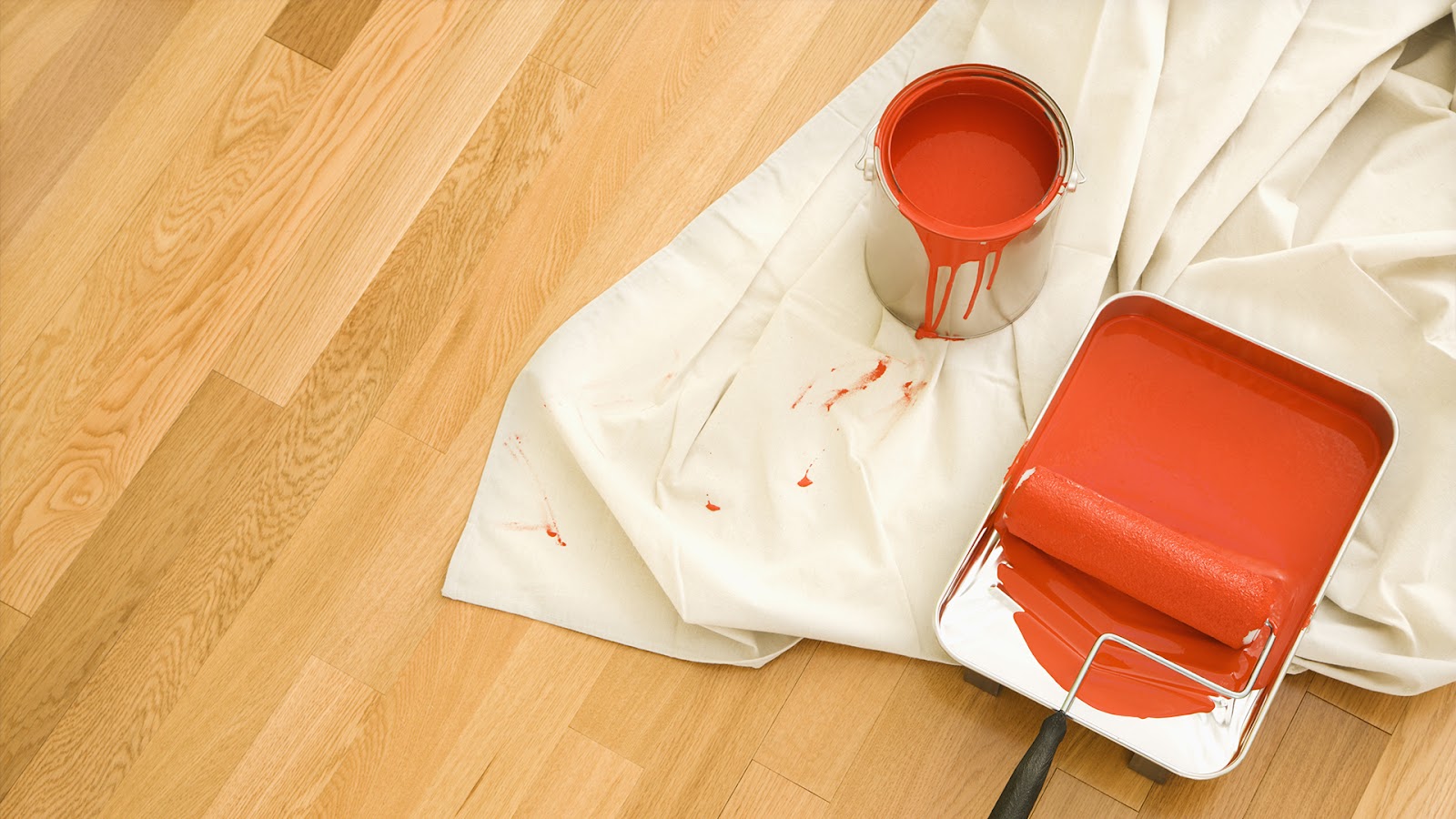 A paint bucket and roller placed on a sheet to avoid any spillage and easy cleanup.