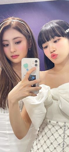 This contains an image of Chaewon and Yunjin taking a selfie in front of a mirror with their cell phones