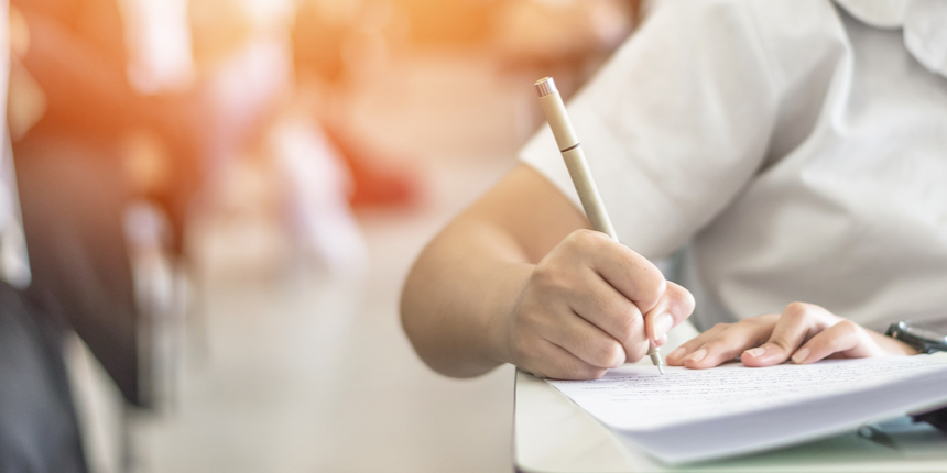 A student writes with a pen on a piece of paper at a desk, perhaps preparing for their NATA exam.