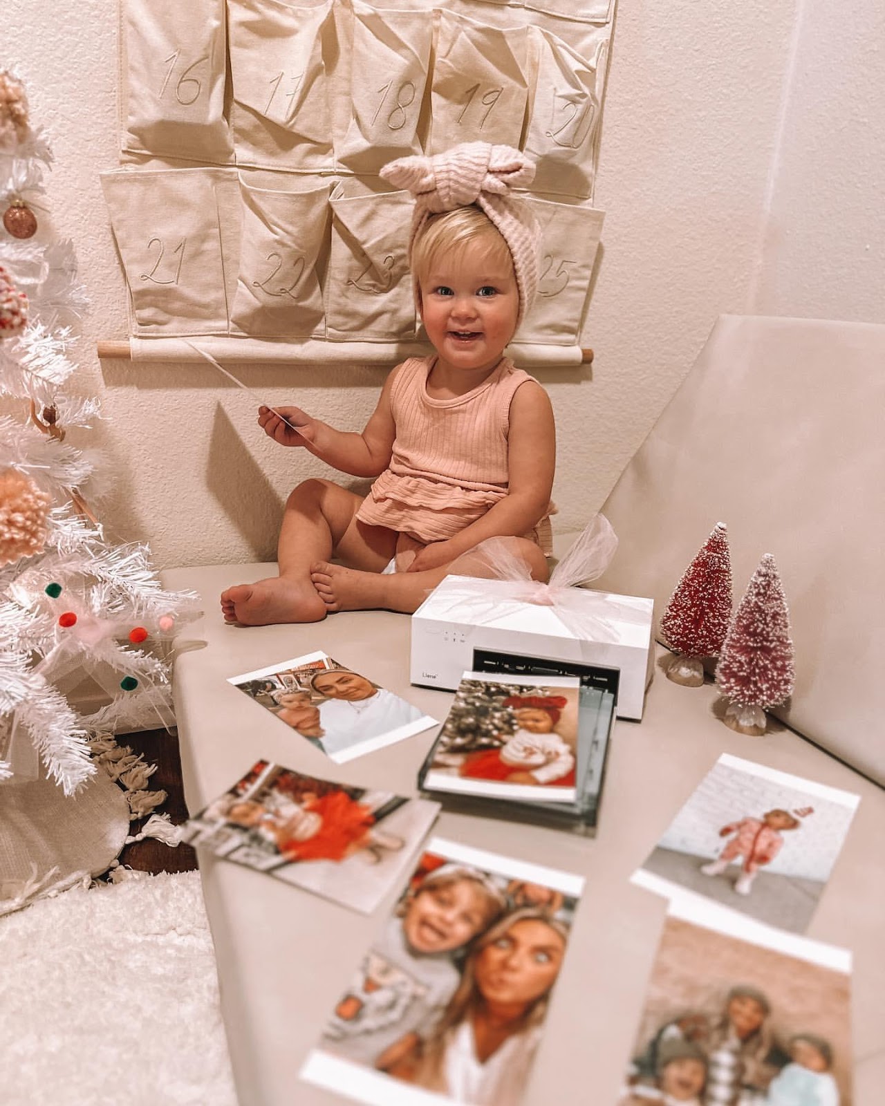 A child sitting on a table with a christmas tree and pictures

Description automatically generated