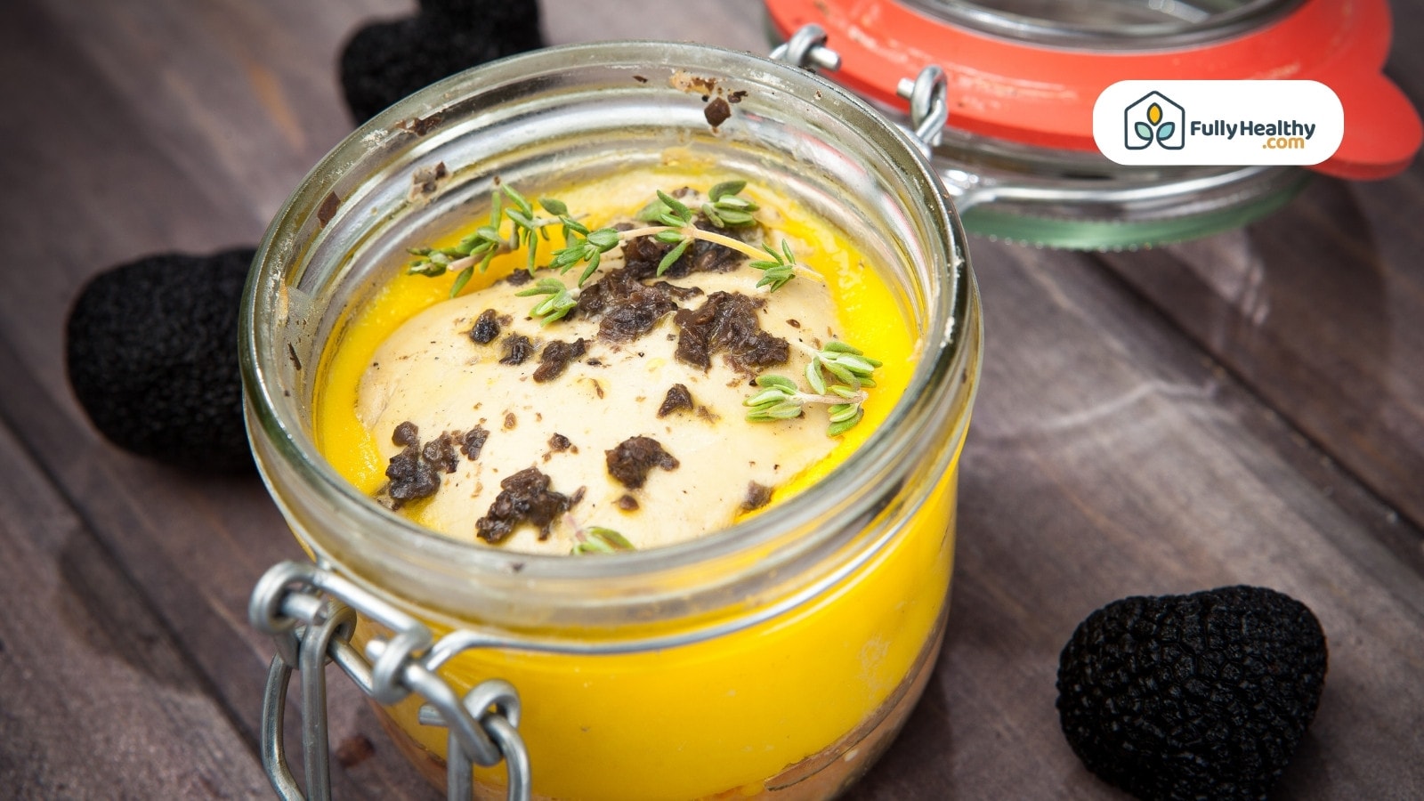 Jar of butter garnished with herbs and black truffles
