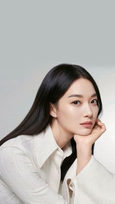 This contains an image of: Shin Min Ah wearing a white shirt with her hand on her jaw 