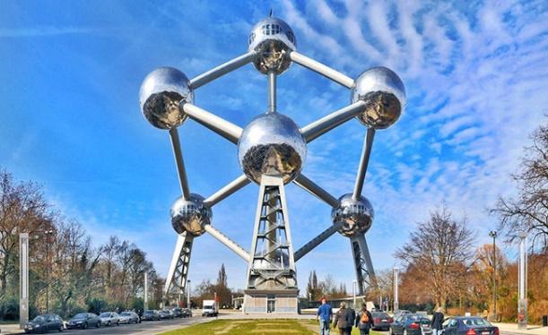 A large metal structure with multiple spheres with Atomium in the backgroundDescription automatically generated