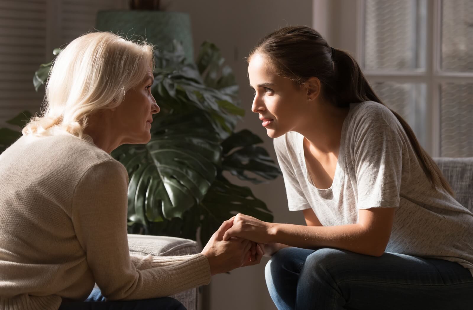 An adult child holding their parent's hand as they have an open conversation about considering assisted living.