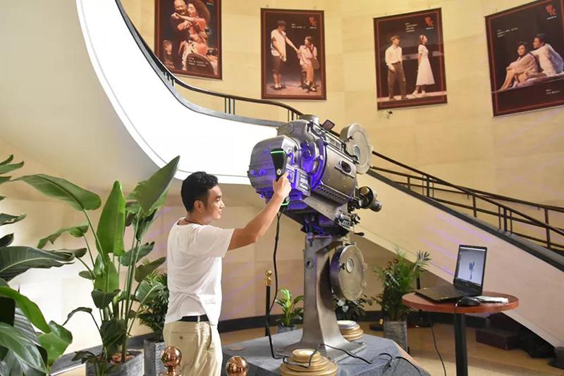 A technician 3D scanning a cinema projector in the theatre