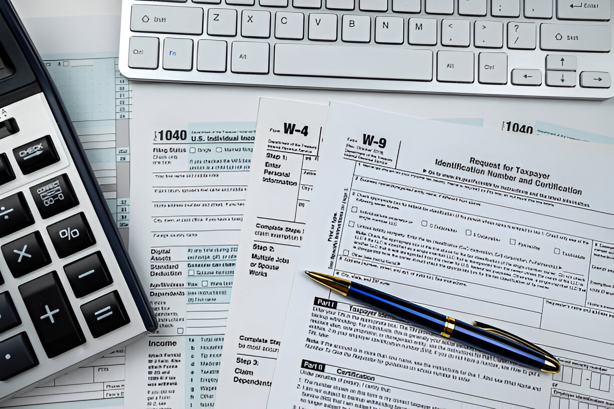 Person using a calculator and analyzing financial charts for bookkeeping and tax preparation.