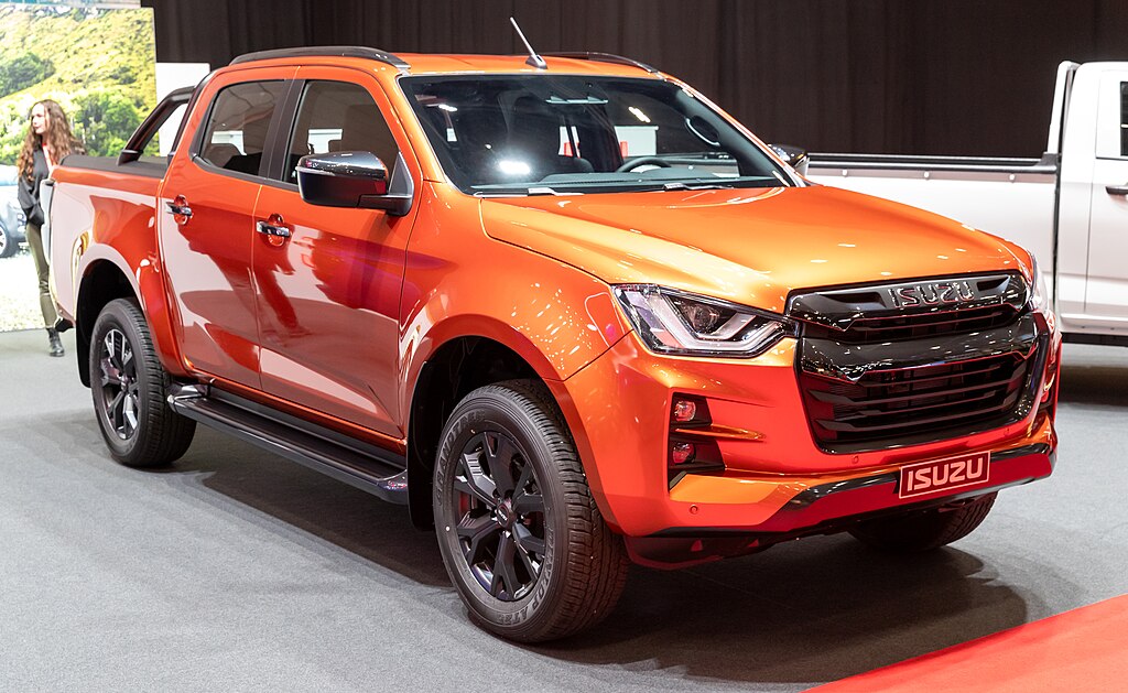 Orange ISUZU truck with fender flares, showcasing a legal solution for wider tire modifications.