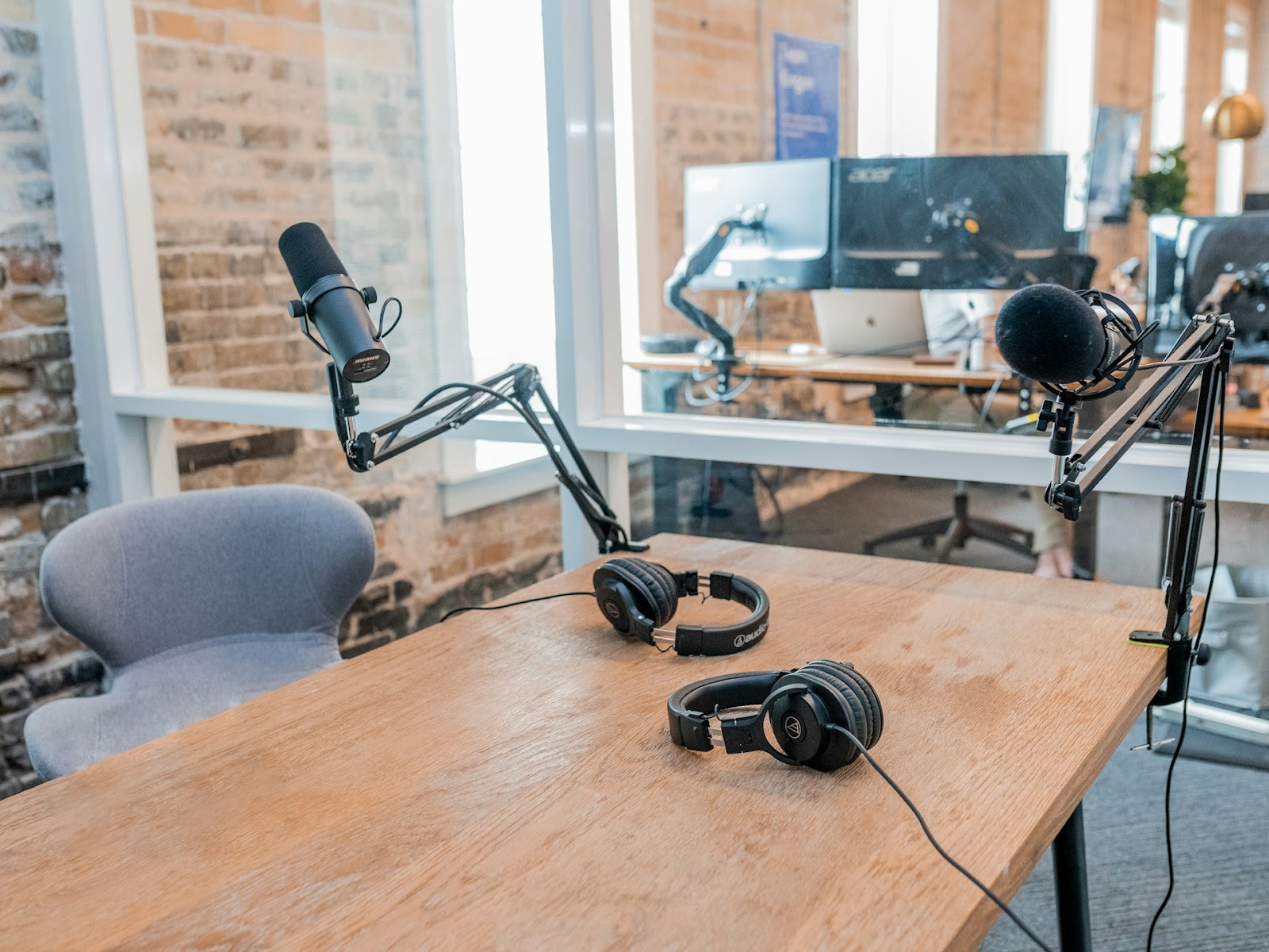 A desk featuring two microphones and a laptop, perfect for recording or podcasting sessions.