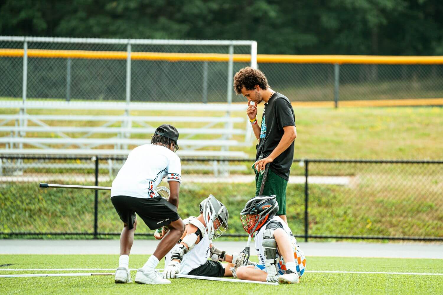 Two coaches are assisting two young lacrosse players with breathing techniques at signature sports camp