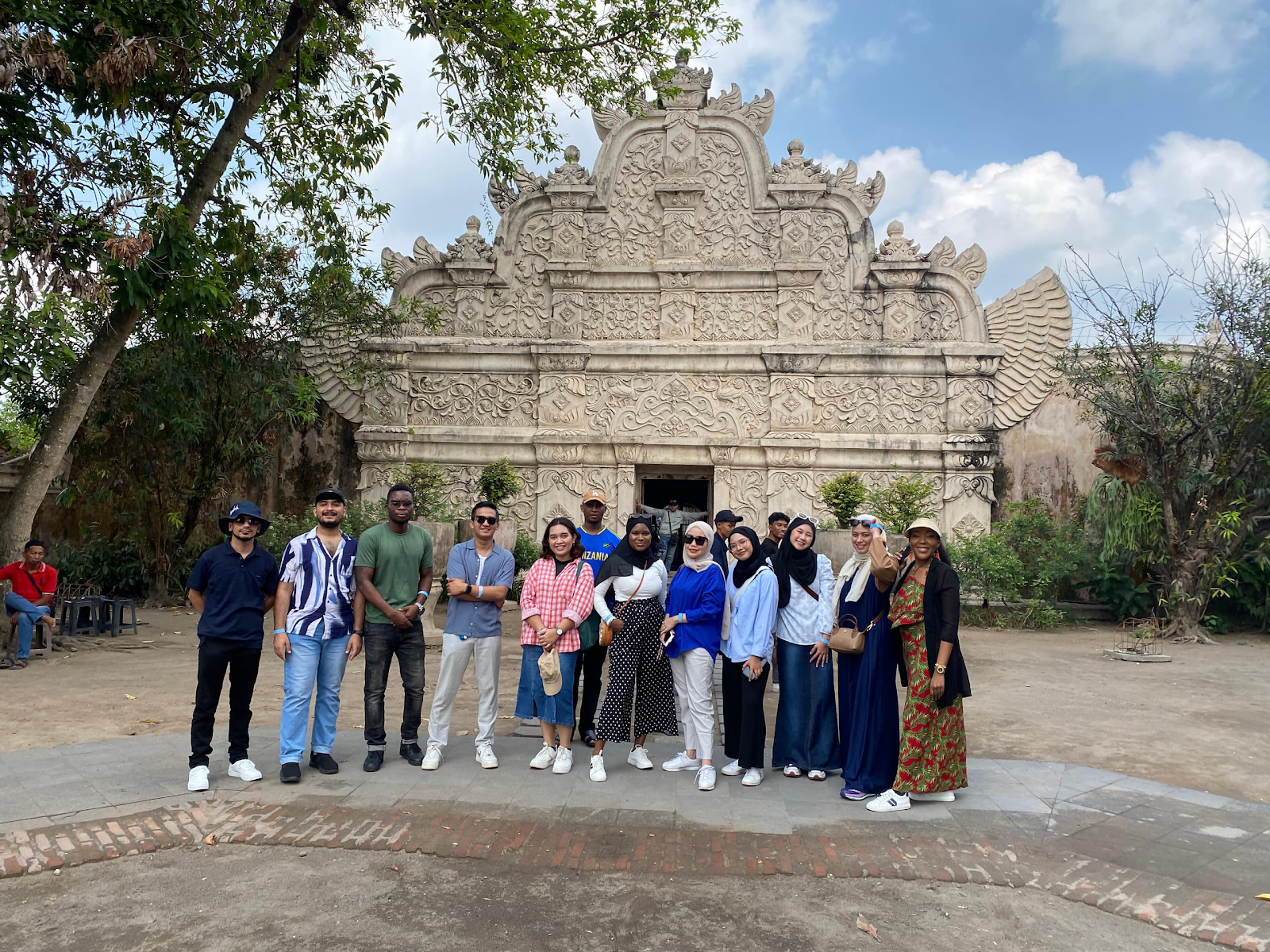 A group of people posing for a photo in front of a stone building

Description automatically generated