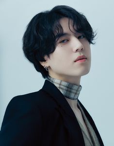 This contains an image of GOT7 Yugyeom with black hair wearing a plaid neck tie and blazer looking off to the side