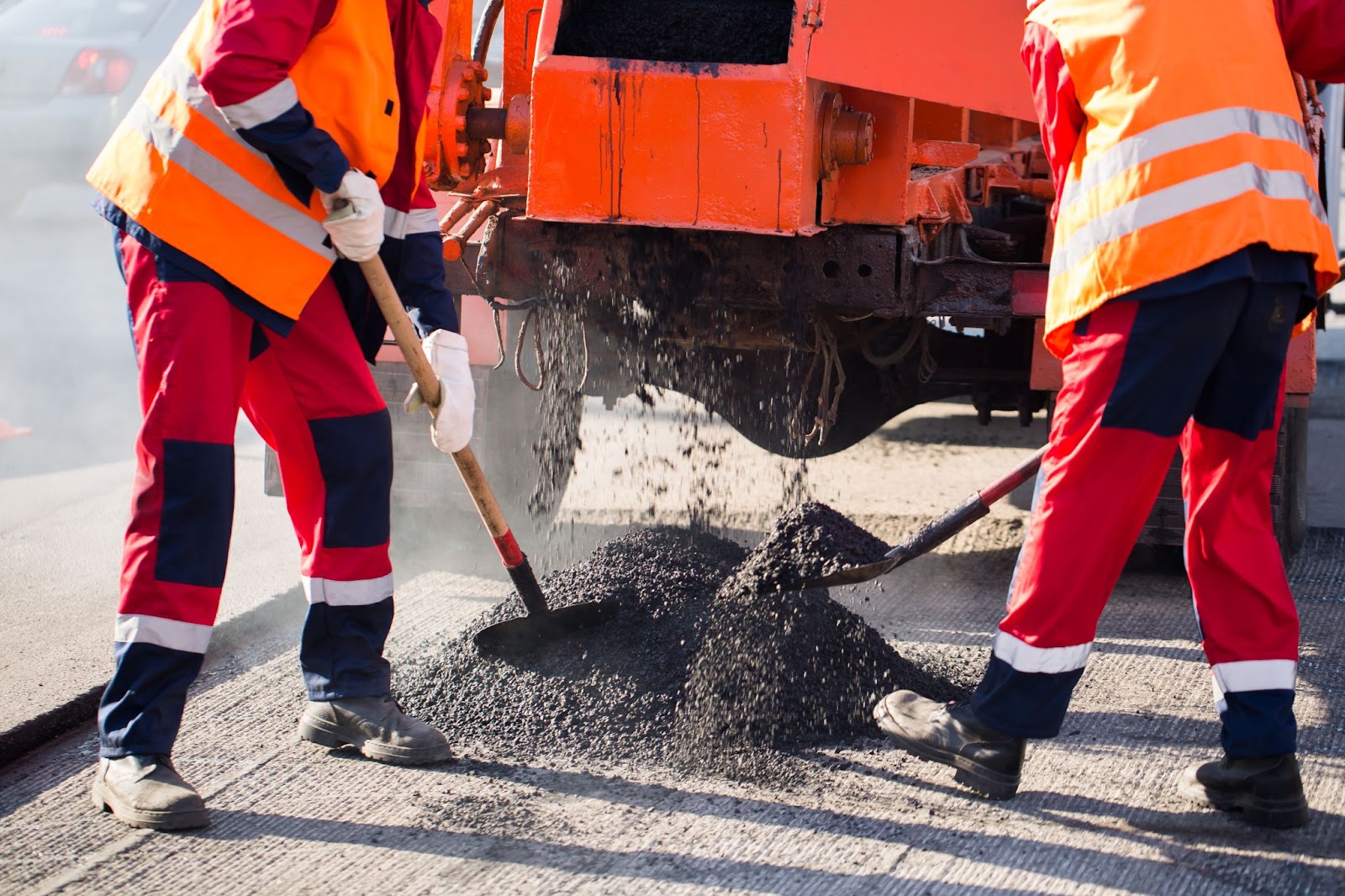 Road workers using construction machines to pave asphalt.