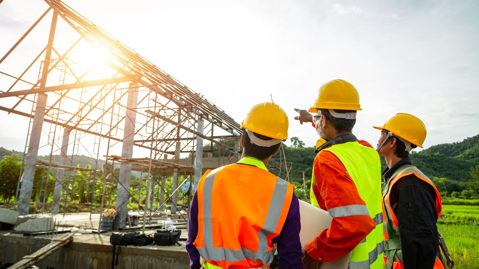 Three people in hard hats standing in front of a construction site