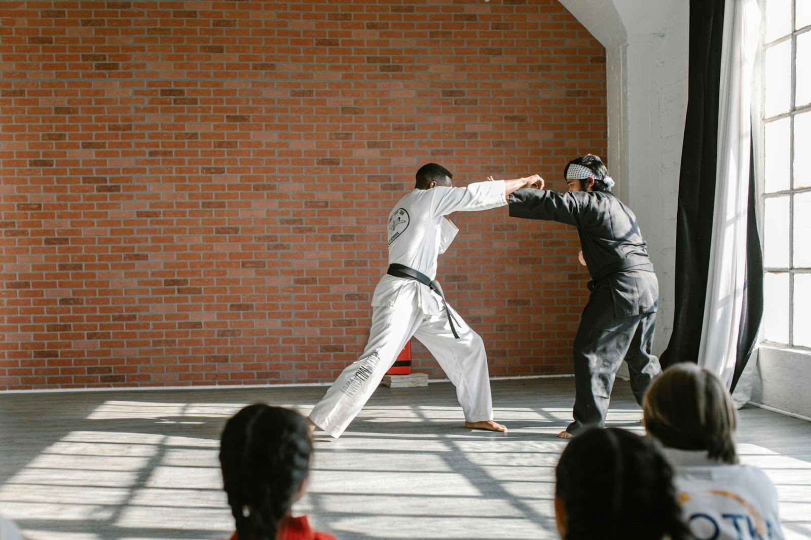 Two martial arts instructors demonstrating defensive moves in front of a class of young students