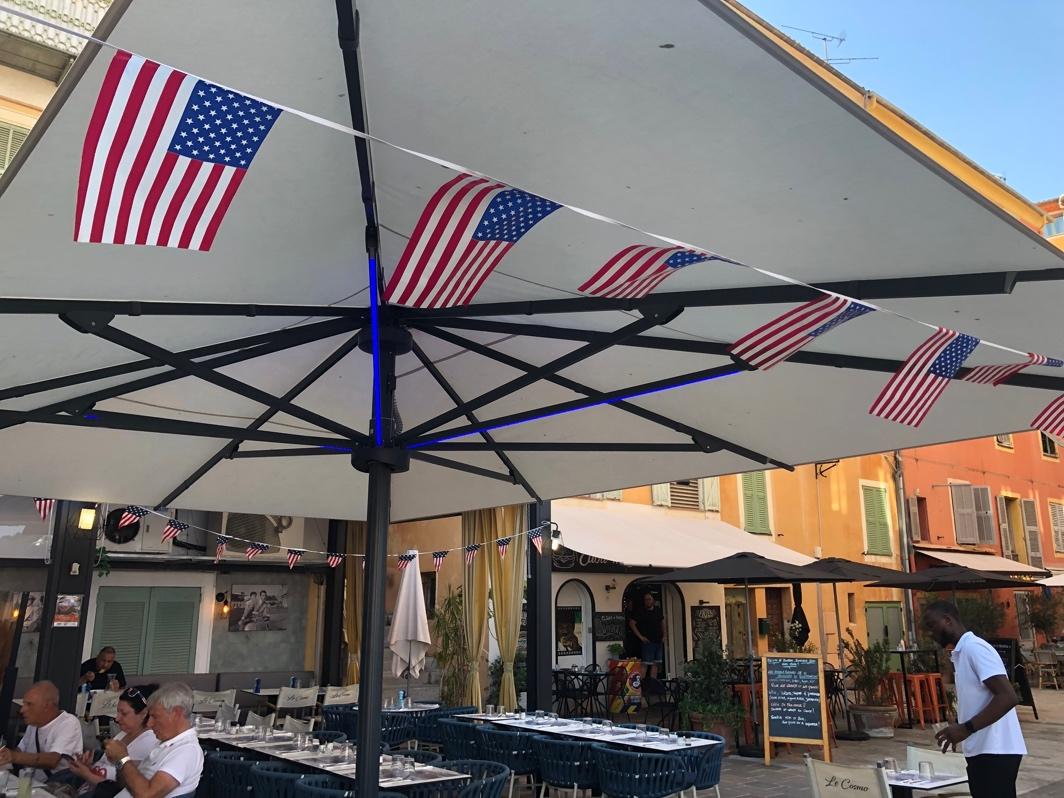 A group of flags on a string under a patio umbrella

Description automatically generated