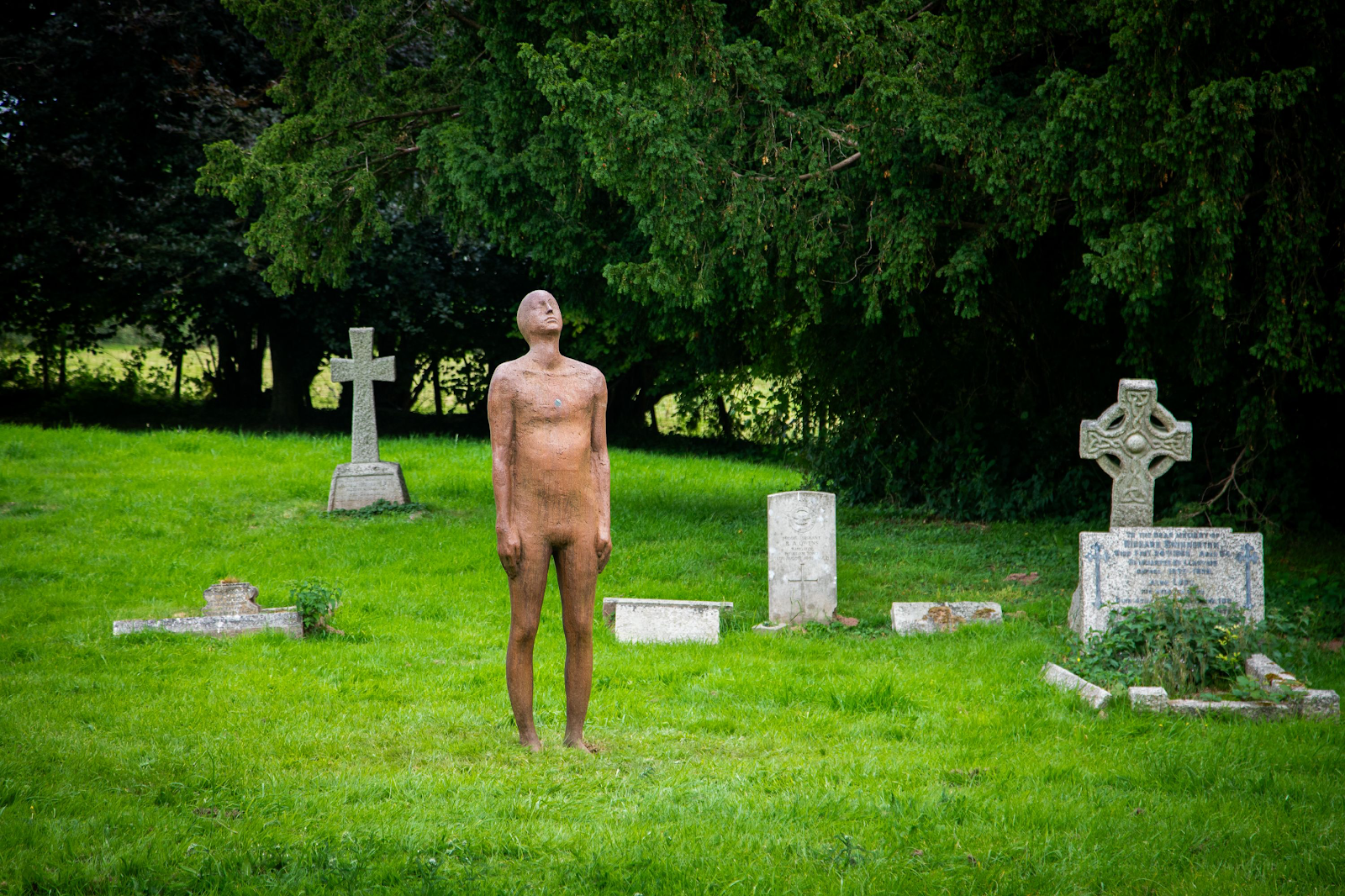 A statue of a person in a cemetery

Description automatically generated