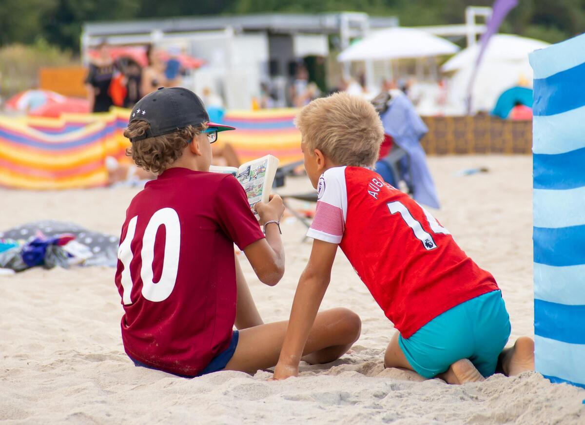 Kids reading on the sandy beach
