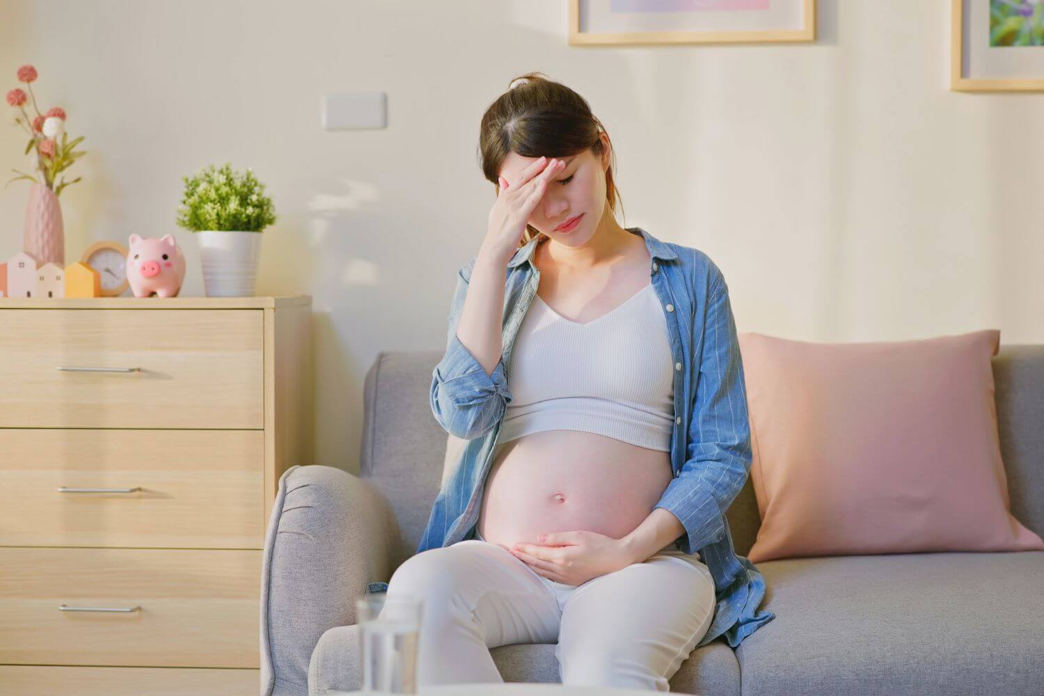 Pregnant woman struggling with depression has her hand on her head