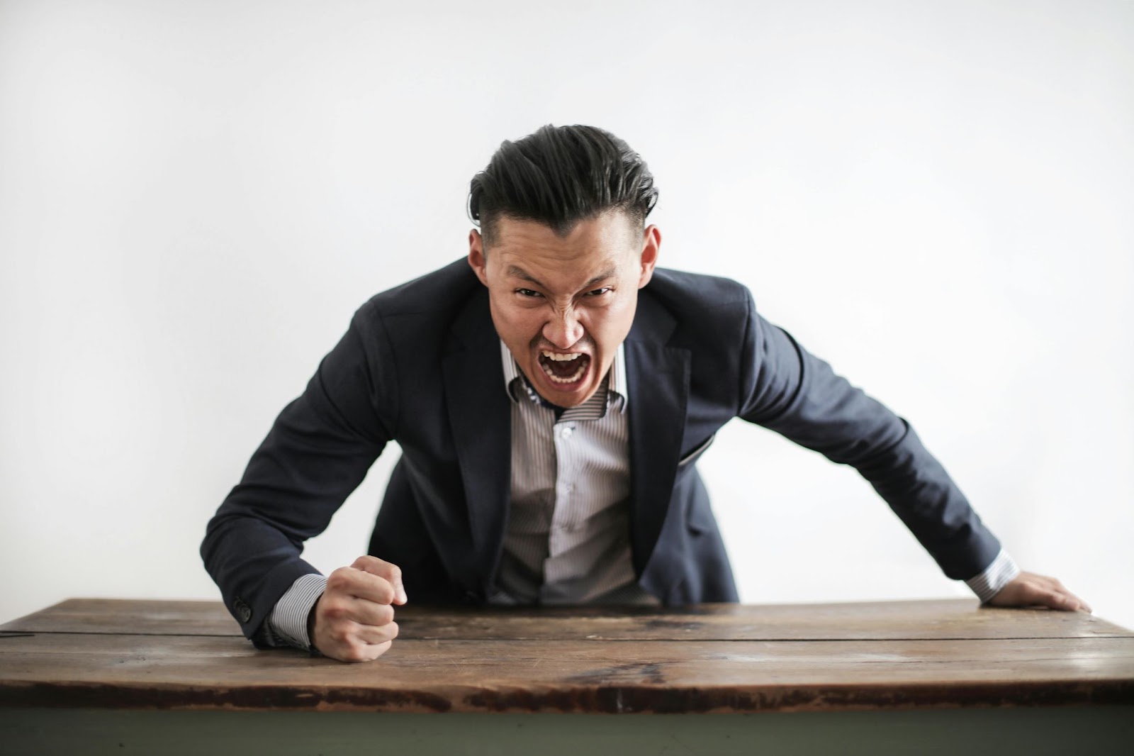 A man slamming his fist on the table in rage