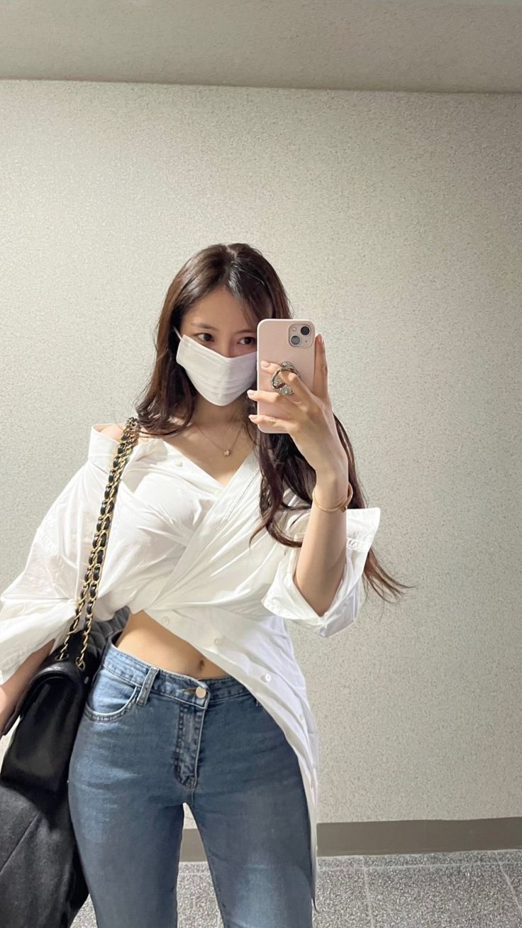 Hyomin wearing a white shirt and a blue jean trouser  and she's hanging a black handbag 