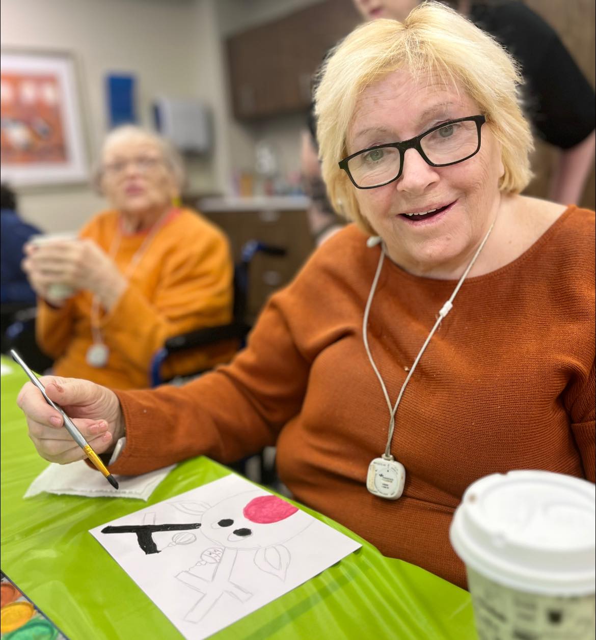 A picture of a woman smiling while painting a picture of a reindeer.