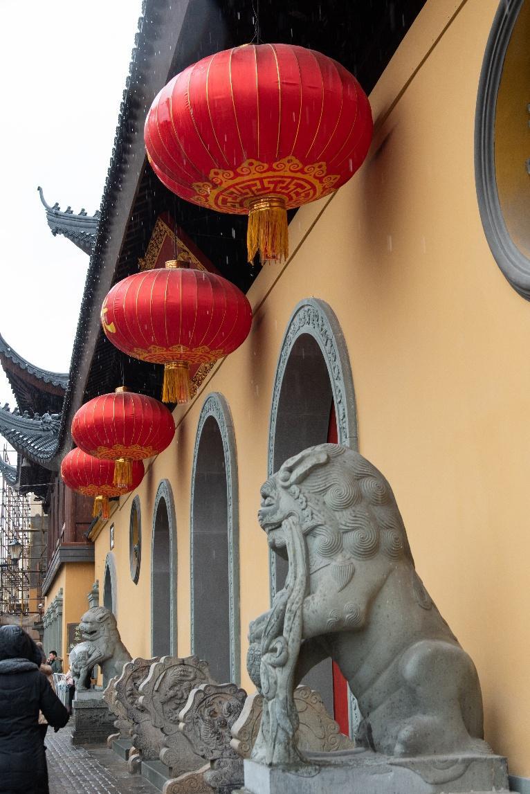 A stone lion statue with red lanterns from a building

Description automatically generated