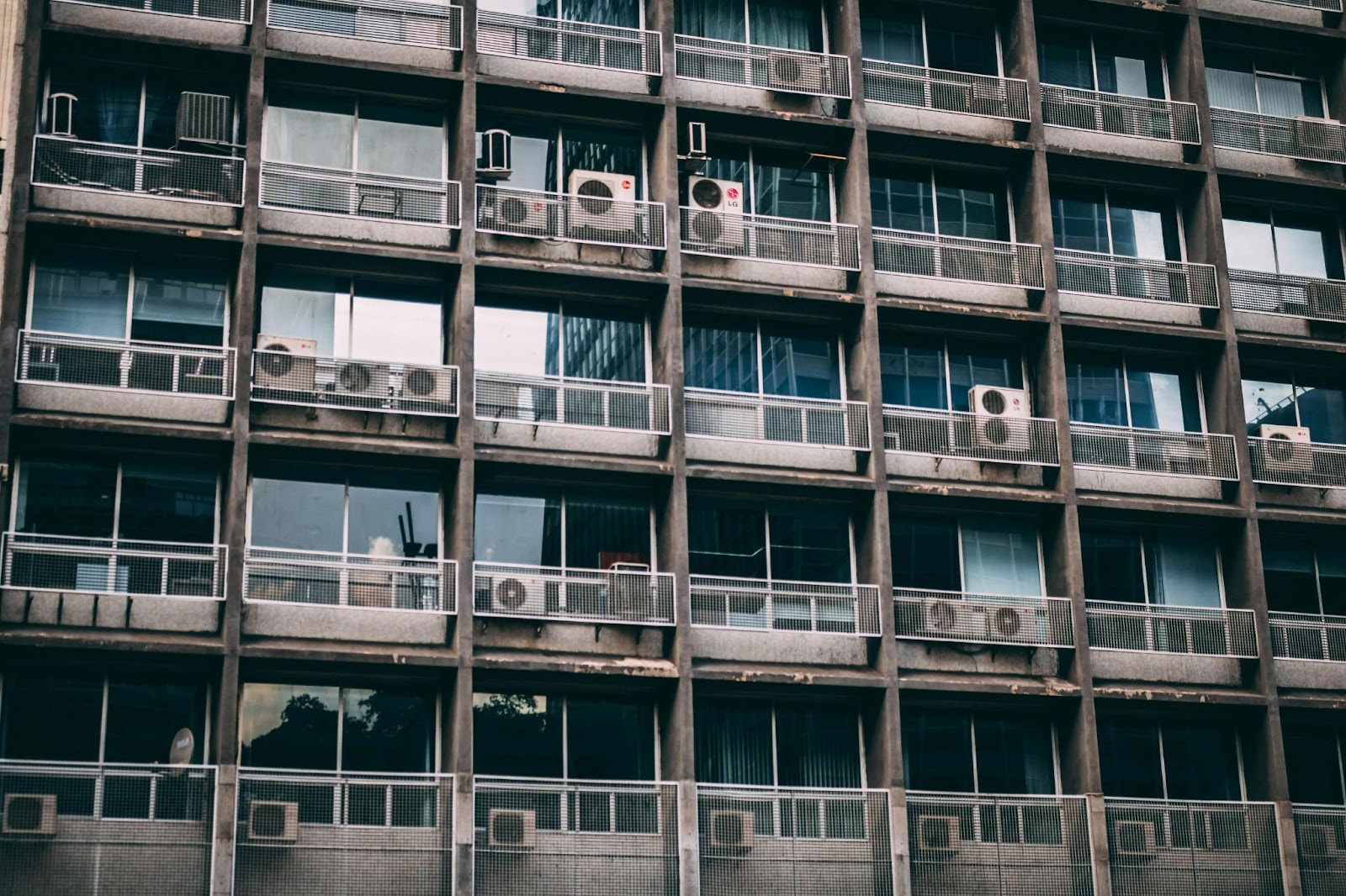 A multi-story apartment building with HVAC units hanging over balconies