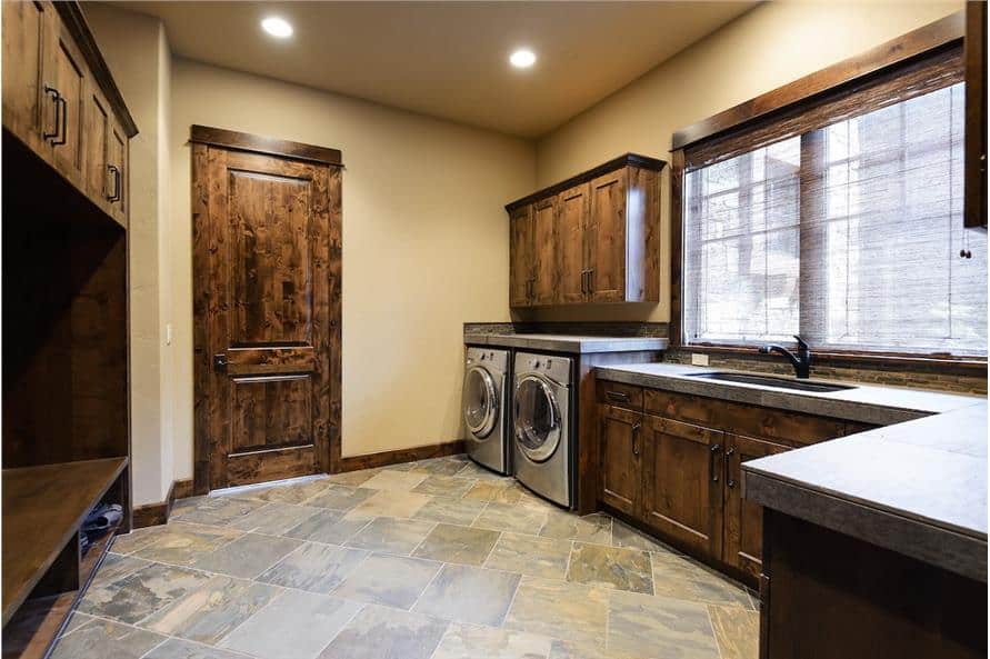 Combined laundry and mudroom with front-load appliances, utility sink, and built-in bench with storage underneath.