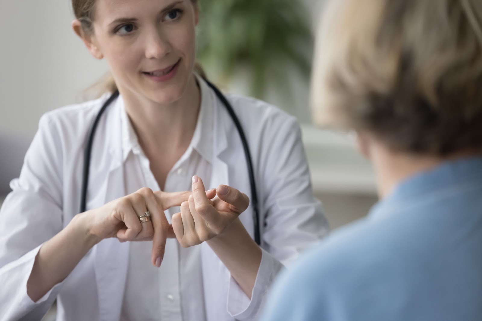 A female doctor uses sign language to communicate with a non verbal patient.