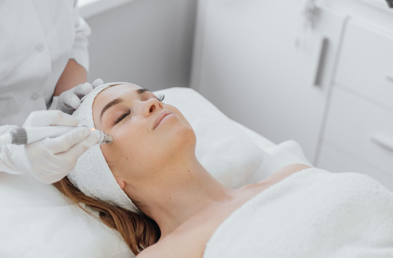 A patient relaxing during an appointment while an esthetician uses radio frequency to get rid of frown lines.