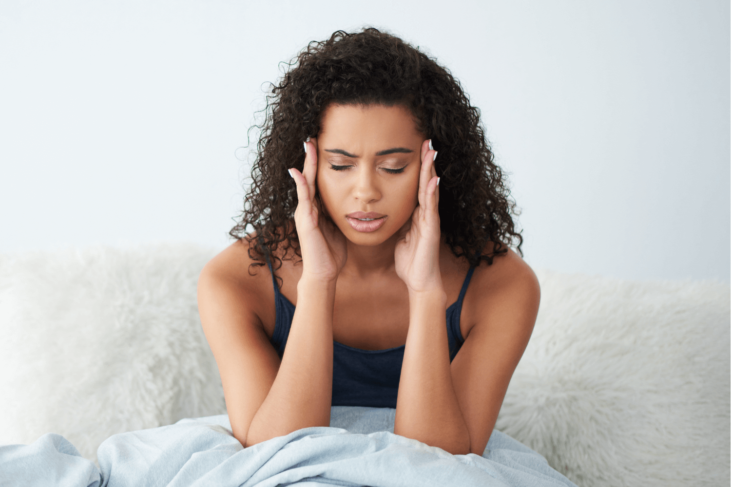 woman holding her hands to her head as she sufferers from fatigue and dizziness as a result of anemia