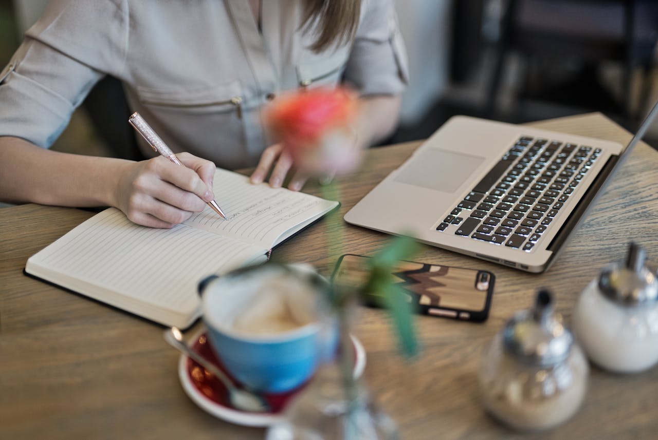  A person infront of a laptop, taking some notes