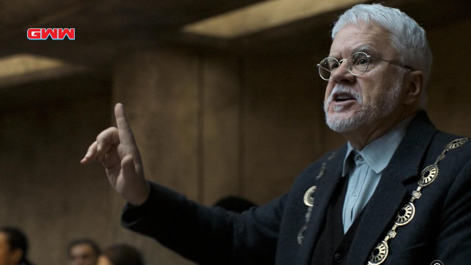 Bernard passionately gesturing during an intense debate in a dark room.