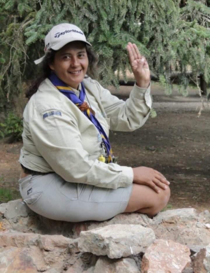 A person sitting on a rock with her hand raised

Description automatically generated