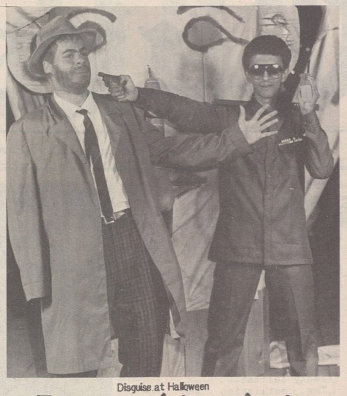 Caravan newspaper clipping photo showing two students in costume, one of them appearing to shoot the other with a fake gun. 